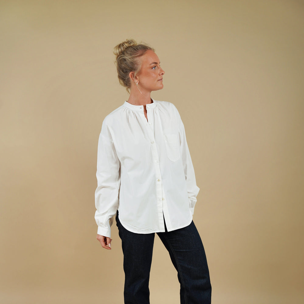 Person wearing a white shirt and black pants on a beige background