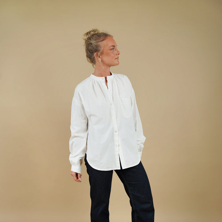 Person wearing a white shirt and black pants on a beige background