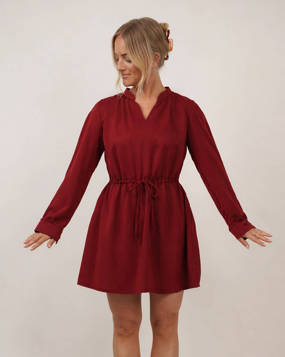 Woman wearing the Grace dress sewing pattern in a red slik on a cream background