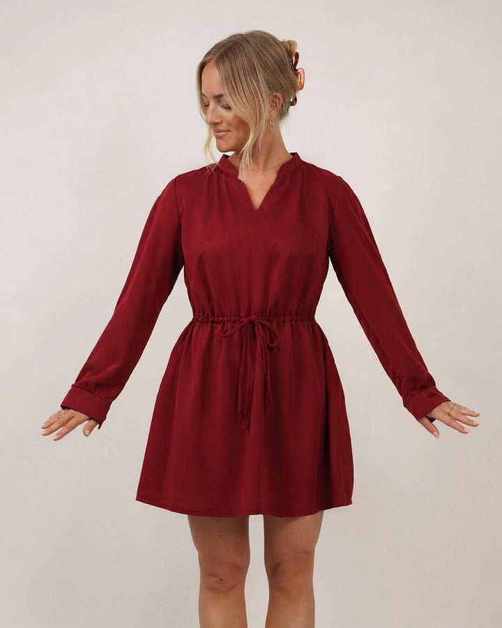 Woman wearing the Grace dress sewing pattern in a red slik on a cream background