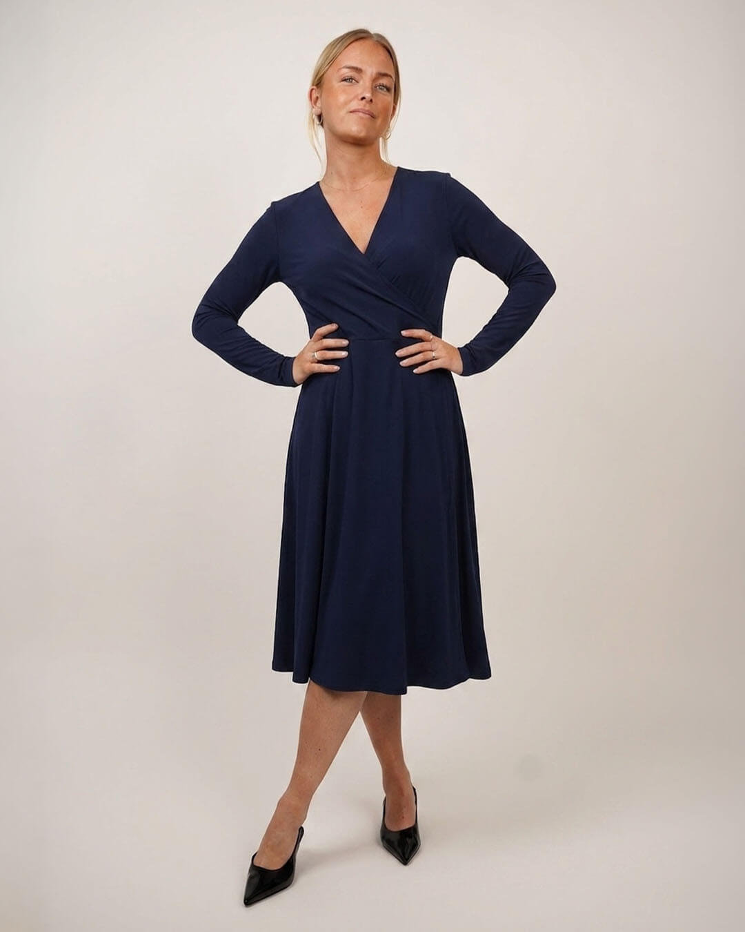 Woman wearing Wanda Wrap dress in blue jersey on cream color background