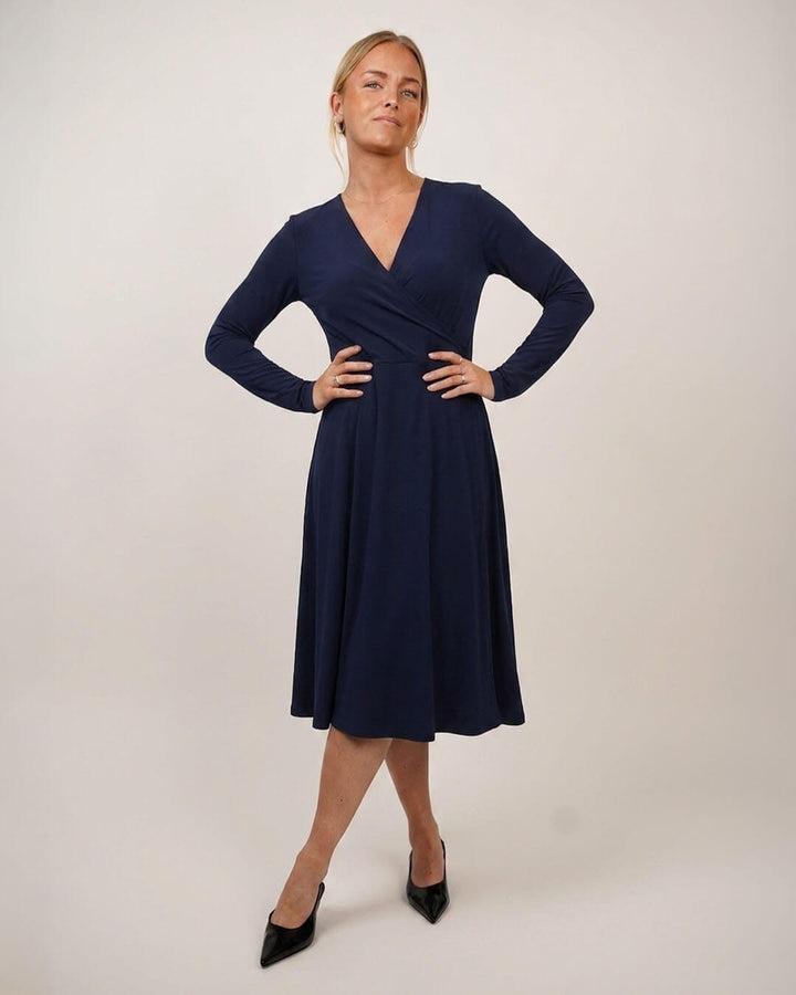 Woman wearing Wanda Wrap dress in blue jersey on cream color background
