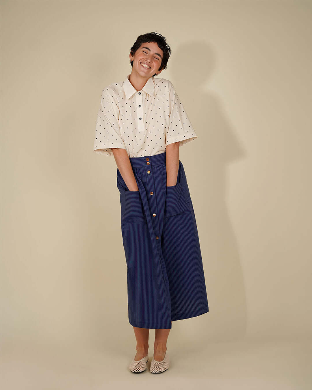 Woman smiling in a polka dot rugby shirt and blue skirt, showcasing the Women's Rugby Shirt Sewing Pattern.