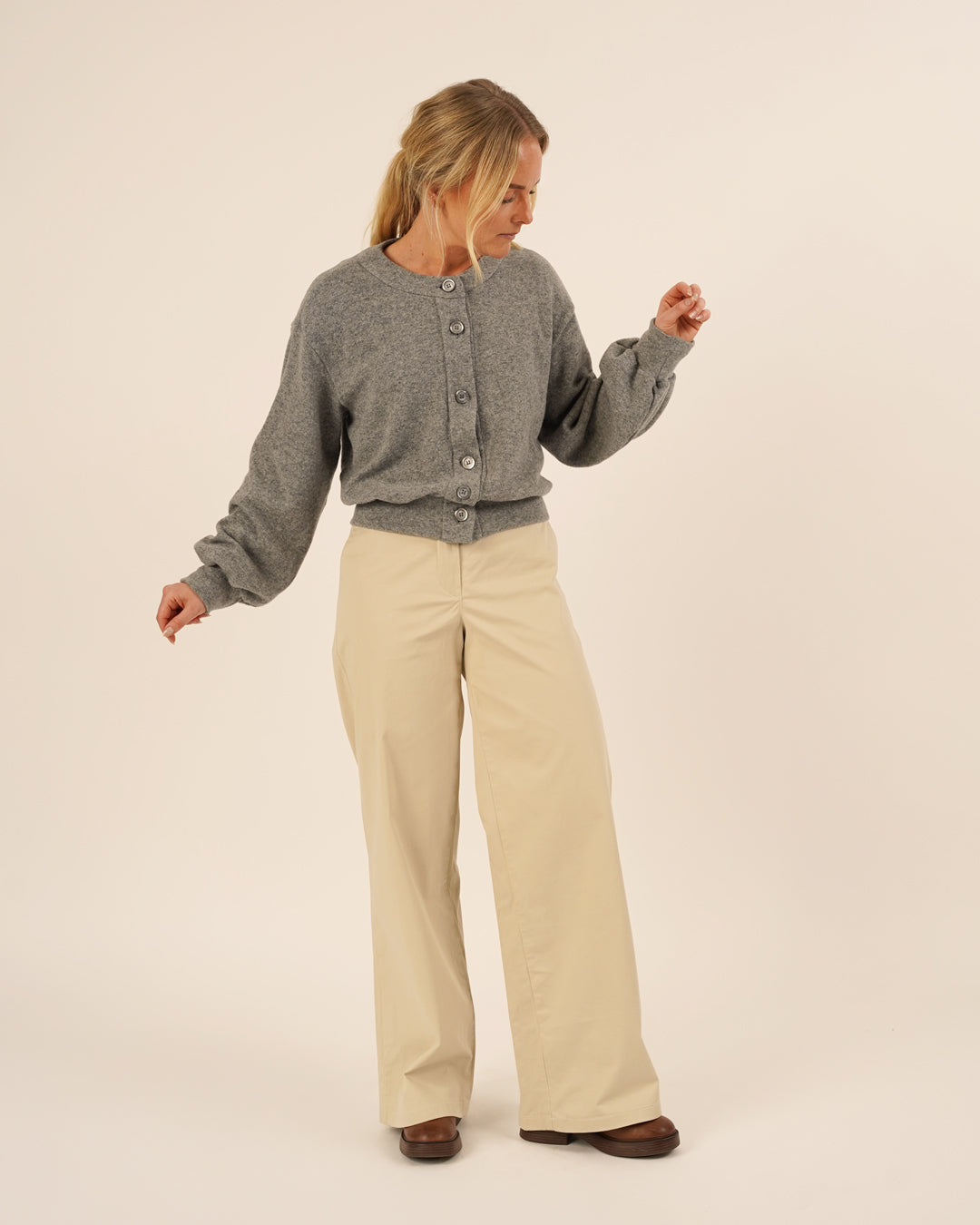 Woman wearing the Balloon Cardigan sewing pattern in grey knit fabric paired with Hepburn Pants in beige cotton twill, shown in a relaxed pose