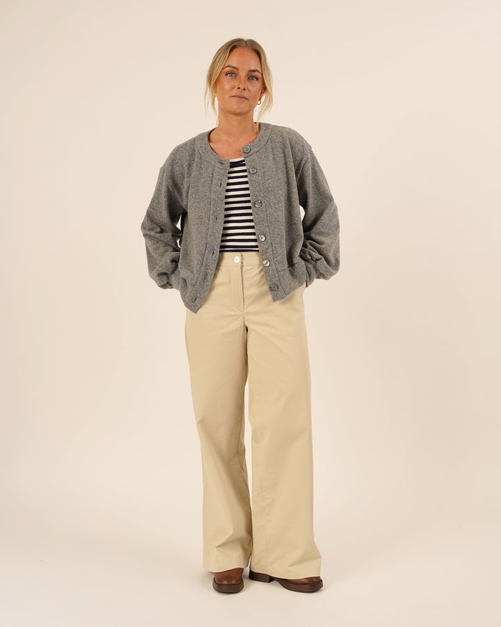 Woman wearing the Balloon Cardigan sewing pattern in grey knit fabric layered over a striped top and paired with Hepburn Pants in beige cotton twill