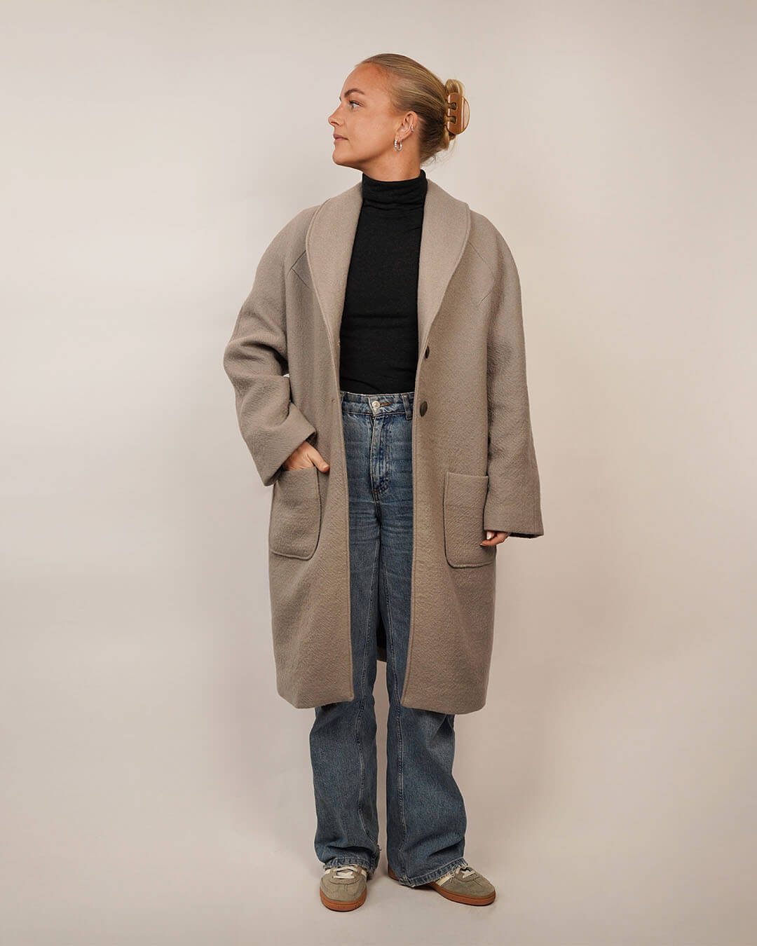 Woman wearing the Cocoon Coat sewing pattern layered over the Trudy Turtleneck knit top and blue jeans, shown from the front