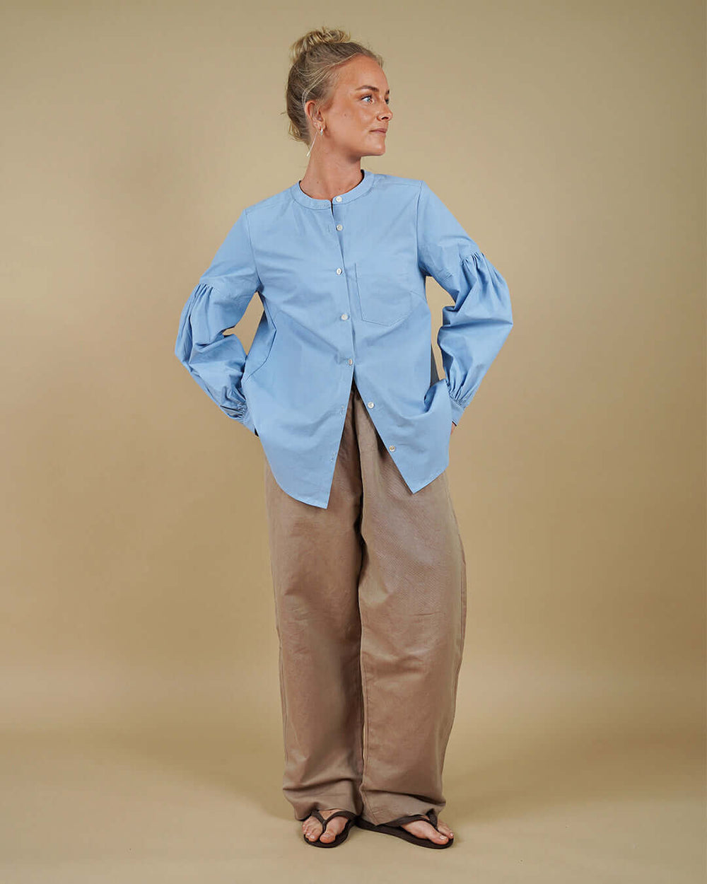 Woman wearing a collarless shirt with gathered sleeves and volume pants sewing pattern, front three-quarter view