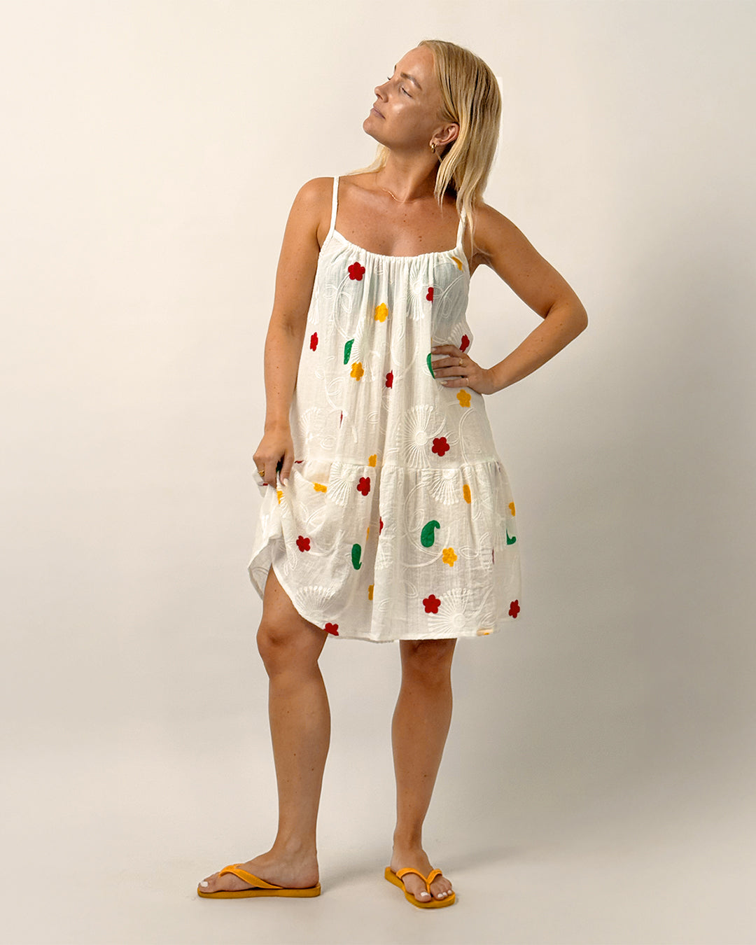 Woman wearing the Skagen Dress sewing pattern in embroidered white cotton with thin straps, gathered bodice, and tiered skirt