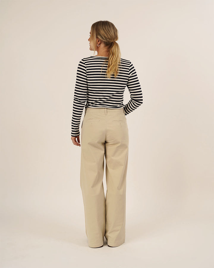 Woman wearing the Wardrobe Builder T-shirt sewing pattern in black and white striped knit paired with Hepburn Pants in beige cotton twill, shown from the back