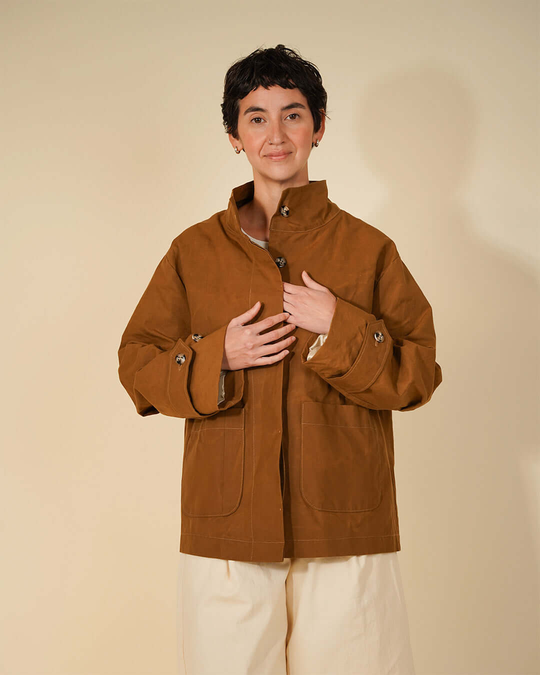 Woman wearing Wardrobe By Me Funnel Neck Jacket sewing pattern in a brown color, showcasing the high collar and relaxed silhouette.